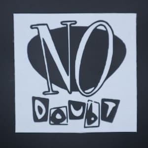 May include: A square, white fabric patch with the words "NO DOUBT" in a black, stylized font. The word "NO" is large and centered above the word "DOUBT", which is in a smaller font. The background is black.