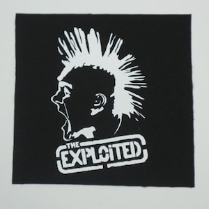 May include: Black square patch featuring a white graphic of a person with a mohawk and open mouth. The text "THE EXPLOITED" is in a white, rectangular box below the graphic. The patch is likely for clothing or accessories.