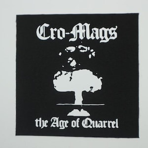May include: Black square patch with white text and graphic. The text reads "Cro-Mags" above a white mushroom cloud graphic. Below the graphic, the text reads "the Age of Quarrel".