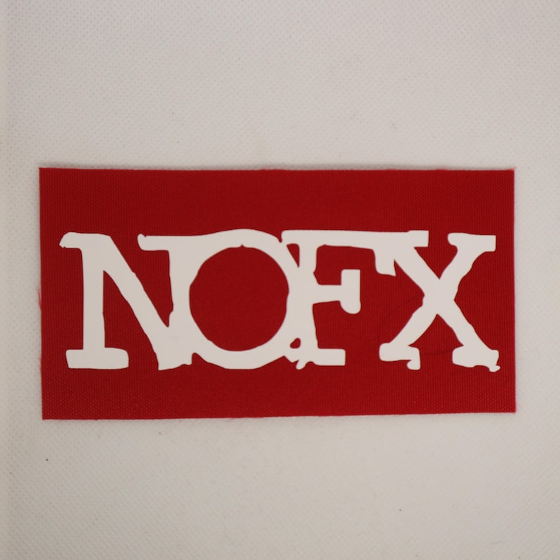 Peut inclure: Un &eacute;cusson rectangulaire rouge avec le texte blanc "NOFX" en gras, dans une police de caract&egrave;res vieillie. L'&eacute;cusson, probablement en tissu, est pos&eacute; sur un fond blanc. Les lettres sont l&eacute;g&egrave;rement irr&eacute;guli&egrave;res, donnant un aspect vintage.