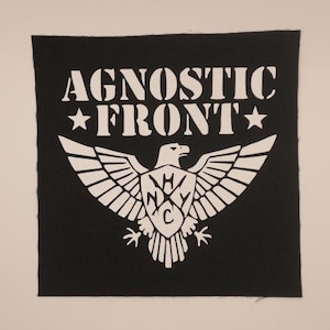 May include: Black square patch with the text "AGNOSTIC FRONT" above a white eagle emblem with outstretched wings. The emblem includes the letters "H", "N", "Y", and "C". Two white stars flank the word "FRONT".