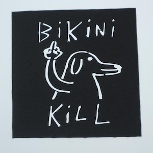 May include: Black square patch with white text and a dog illustration. The text reads "BIKINI KILL" with a dog giving the middle finger. The dog is drawn in a simple, cartoon style.