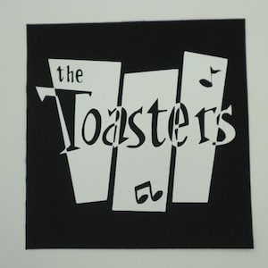 May include: Black square patch with the text "the Toasters" in a stylized white font. The design includes three white vertical rectangles and musical notes. The patch is likely for clothing or accessories.