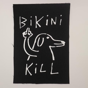 May include: Black fabric patch with white text and a cartoon dog. The text reads "Bikini Kill".