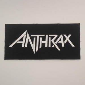May include: White "Anthrax" logo patch on a black fabric background.