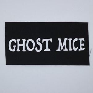 May include: A black rectangular patch with the words "GHOST MICE" in bold white letters. The patch has a ribbed texture and is likely made of fabric. The text is centered on the patch.