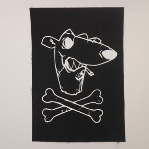 May include: White iron-on patch with a cartoon dog smoking a cigarette and a skull and crossbones design on a black background.