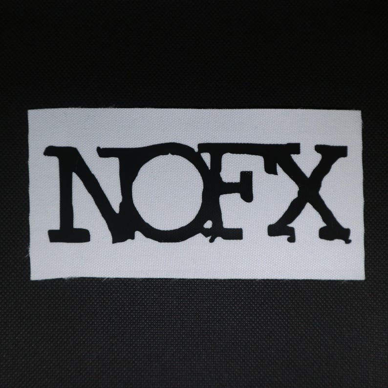 Peut inclure: Un &eacute;cusson rectangulaire blanc avec le texte noir "NOFX". Les lettres sont en gras et stylis&eacute;es, avec une police distinctive. L'&eacute;cusson est probablement destin&eacute; aux v&ecirc;tements ou aux accessoires.
