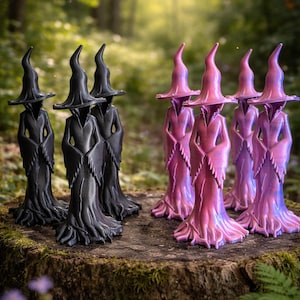 May include: A collection of witch figurines in black and iridescent pink and purple hues. The figures are standing on a moss-covered tree stump in a forest setting. The witch figures have pointed hats and flowing robes.