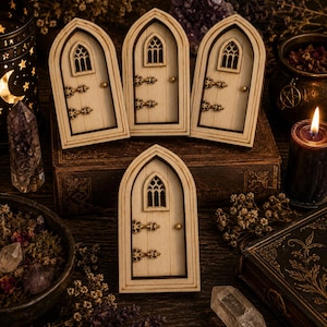 May include: Four light-colored wooden miniature doors with arched tops, each featuring a small arched window with decorative cutouts, two dark metal-look hinges on the left side, and a small round knob on the right side of the door panel.