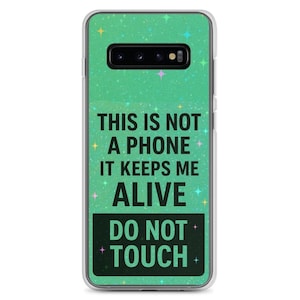 Puede incluir: Funda de teléfono transparente con un fondo verde brillante y el texto "THIS IS NOT A PHONE IT KEEPS ME ALIVE DO NOT TOUCH" en negro. La funda tiene un recorte para la cámara y un borde transparente.
