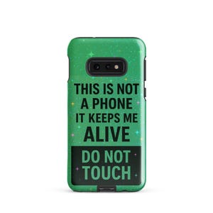 May include: A green phone case with the text "THIS IS NOT A PHONE IT KEEPS ME ALIVE DO NOT TOUCH". The case has a glittery effect and a black camera cutout.