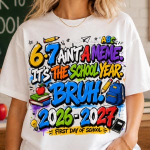 May include: A white t-shirt featuring a colorful graphic with the text 6-7 AINT A MEME. IT'S THE SCHOOL YEAR. BRUH. 2026-2027 FIRST DAY OF SCHOOL. The design includes illustrations of a pencil, an apple on books, a backpack, a lightbulb, and a notebook.