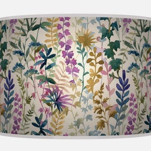May include: A cylindrical lampshade with a watercolour floral design. The pattern features plants in shades of purple, green, blue, and yellow against a cream background. The design has a botanical theme.