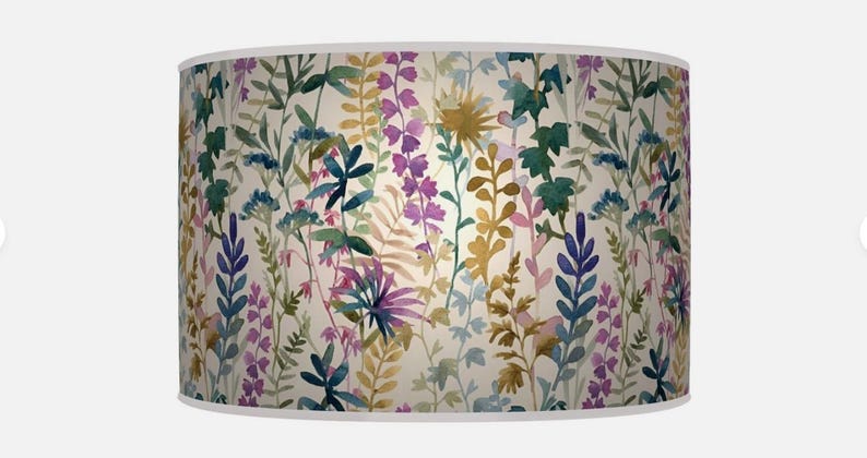 May include: A cylindrical lampshade with a watercolour floral design. The pattern features plants in shades of purple, green, blue, and yellow against a cream background. The design has a botanical theme.