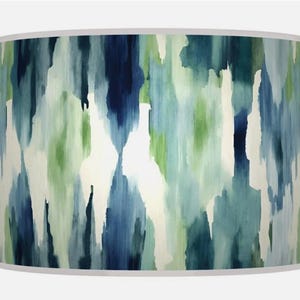 May include: Cylindrical lampshade with a watercolour-style design. The pattern features vertical strokes of blue, green, and white, creating a textured, abstract look. The top and bottom edges are finished with a white trim.