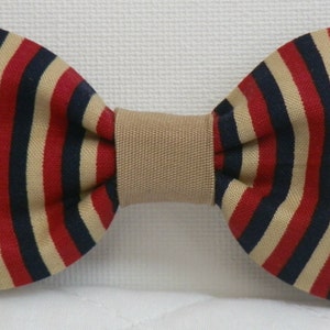 May include: A striped bow tie with alternating red, navy, and tan vertical stripes. The center band is a solid tan color. This formal accessory is suitable for special occasions.