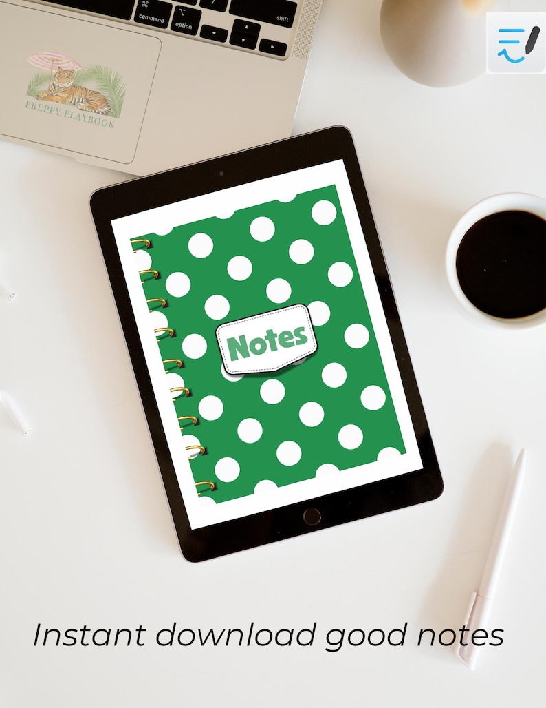 May include: A digital tablet displaying a green notebook cover with a white polka dot pattern and a central white label featuring the word Notes in green text. The notebook has a gold spiral binding on the left side and is shown on a white desk.