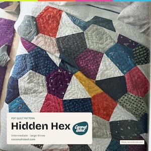 May include: A quilt featuring a geometric pattern of multicolored hexagonal shapes in shades of red, blue, yellow, purple, and black, interspersed with white fabric. A label reads: PDF QUILT PATTERN Hidden Hex, Intermediate, large throw, coconutrobot.com.