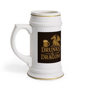 Pode incluir: Caneca de cerveja de cerâmica branca com borda e alça douradas. Um retângulo preto na frente apresenta uma ilustração dourada de um caneco de cerveja e um dragão, com as palavras "Drunks & Dragons" em ouro.
