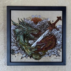 May include: Square framed artwork featuring two dragons facing each other with a sword between them. One dragon is green and the other is red. The background includes clouds and a sun design. The artwork is signed and dated.
