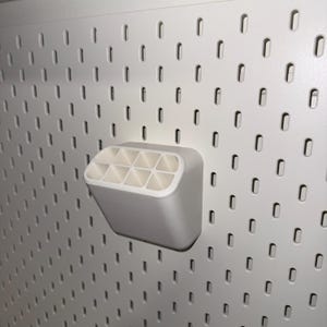 May include: White plastic wall-mounted organiser with nine compartments. The organiser is mounted on a white pegboard.