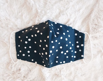 Mascarilla facial de triple capa con lunares azul marino y bolsillo para filtro, lavable para múltiples usos.