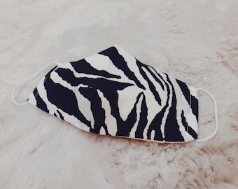 May include: A white and black zebra print face mask with elastic ear loops.