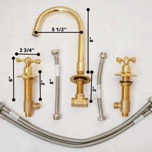 May include: A new gold-colored bathroom faucet set with a gooseneck spout, two cross-handle valves, and flexible supply lines. The faucet is 5 1/2 inches wide and 8 inches tall. The valves are 6 inches tall and 2 3/4 inches wide.