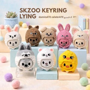 Pode incluir: Uma coleção de oito chaveiros de animais de crochê. Cada chaveiro apresenta um design de animal diferente, incluindo um coelho, um urso, um cão e um pintinho. Os chaveiros são em várias cores, como branco, castanho, rosa e amarelo. O texto "SKZOO KEYRING LYING" é exibido no topo.