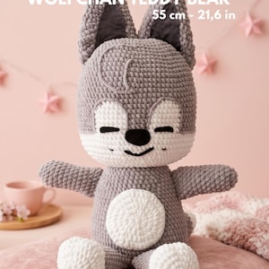 Peut inclure: Un ours en peluche Wolfchan crocheté, de 55 cm de haut, en gris et blanc. Le jouet en peluche a de grandes oreilles, un ventre blanc et des pattes blanches. Le texte "WOLFCHAN TEDDY BEAR" est affiché au-dessus de l'ours.