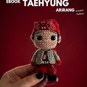 May include: A crochet amigurumi doll featuring a red bandana with a white paisley pattern, a light gray textured jacket, and a red skirt. The doll has large black eyes and is presented as an EBOOK TAEHYUNG ARIRANG Crochet Pattern.