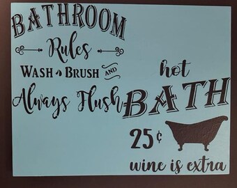 May include: A light blue wooden sign with black text that reads "Bathroom Rules: Wash, Brush, Always Flush, Hot Bath, 25¢, wine is extra." A silhouette of a bathtub is also included.