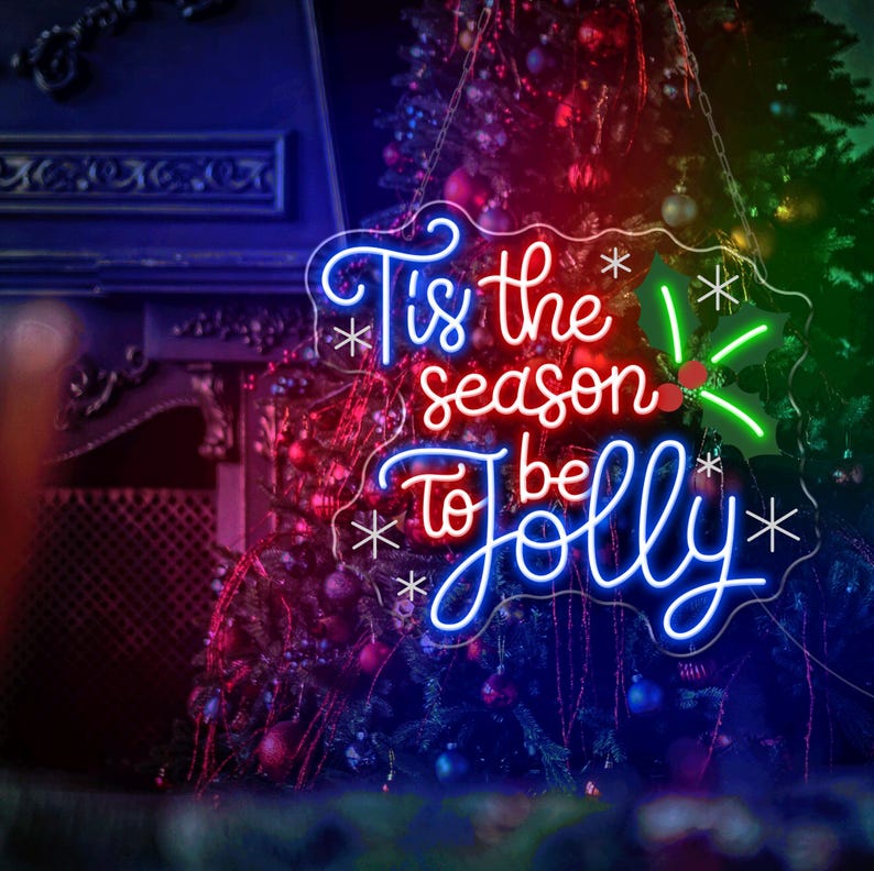 May include: A neon sign with the words "Tis the season to be Jolly" in blue and red, with holly accents. The sign hangs in front of a Christmas tree decorated with ornaments. The background has a fireplace.