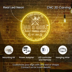 May include: A neon sign for "Henry's Bar & Grill" with a circular design, featuring text and a logo of crossed utensils. The sign is illuminated in a warm yellow glow, with additional components like a mounting kit, power adapter, and remote control.