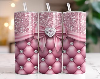 Può includere: Tre bicchieri rosa glitterati con cannucce. Ogni bicchiere presenta un fiocco rosa con un gioiello a forma di cuore, un motivo trapuntato e strass scintillanti. I bicchieri hanno un'estetica glamour.