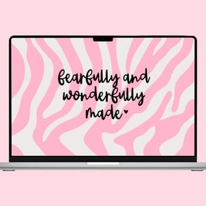Könnte beinhalten: Ein silberner Laptop zeigt ein rosa-weißes Zebramuster auf seinem Bildschirm mit den Worten "fearfully and wonderfully made" in schwarzer Schrift. Der Laptop befindet sich vor einem hellrosa Hintergrund.