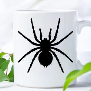 May include: White ceramic mug featuring a black silhouette of a spider. The spider has eight legs and a round abdomen. The mug has a curved handle and is suitable for hot or cold beverages. The design is simple and bold, perfect for Halloween.