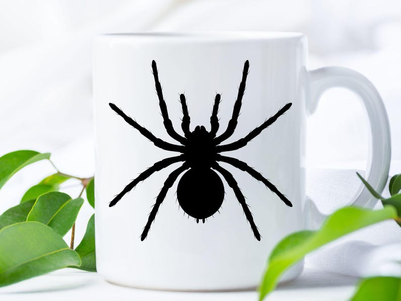 May include: White ceramic mug featuring a black silhouette of a spider. The spider has eight legs and a round abdomen. The mug has a curved handle and is suitable for hot or cold beverages. The design is simple and bold, perfect for Halloween.