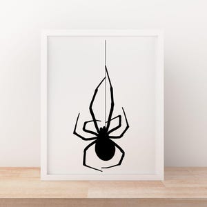 May include: A framed print featuring a black spider silhouette hanging from a thin line against a white background. The spider has a rounded body and long, slender legs. The artwork is displayed in a white frame, creating a minimalist aesthetic.