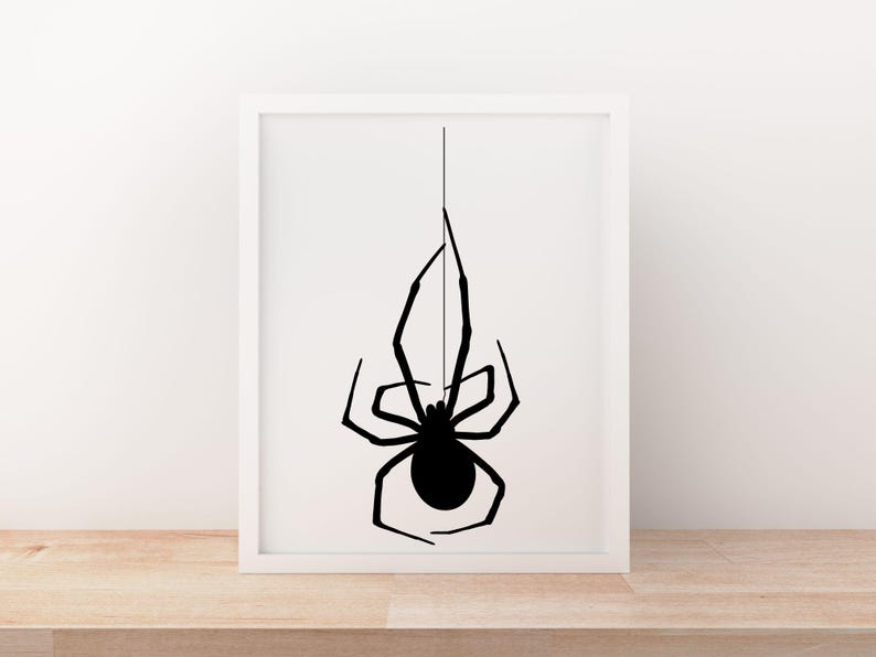 May include: A framed print featuring a black spider silhouette hanging from a thin line against a white background. The spider has a rounded body and long, slender legs. The artwork is displayed in a white frame, creating a minimalist aesthetic.