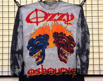 May include: Long-sleeved shirt with a tie-dye effect. The shirt features the name "Ozzy Osbourne" in red and the image of two snarling, fiery-haired demons. The shirt's design is printed on a gray and black background.