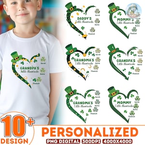 May include: A white t-shirt featuring a heart-shaped design with a green leprechaun hat, shamrocks, and the text "Grandpa's Little Shamrocks." The design includes names and is part of a personalized collection with over 10 designs.