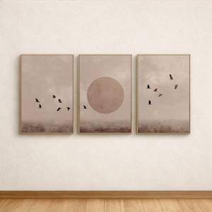 Puede incluir: Conjunto de tres impresiones artísticas enmarcadas. Cada impresión presenta un paisaje en tonos sepia con aves en vuelo. La impresión central incluye una gran forma circular, que se asemeja a un sol o una luna.