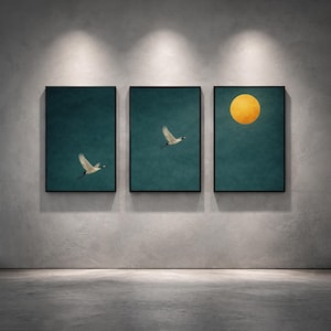 May include: Three framed art prints. Each print has a teal background with a black frame. Two prints feature a white bird in flight. The third print has a large yellow sun. The prints are displayed on a gray wall.