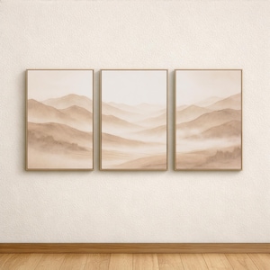 Puede incluir: Tres impresiones artísticas enmarcadas de paisajes. Cada impresión presenta una serena escena de cordillera en tonos beige y marrón, con una atmósfera brumosa. Los marcos son de color dorado, añadiendo un toque de elegancia.
