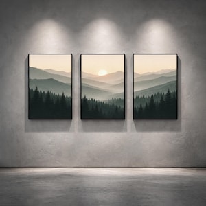 May include: Three framed landscape art prints. Each print depicts a mountain range scene with a forest in the foreground and a sunset in the background. The colour palette includes shades of green, grey, and beige.
