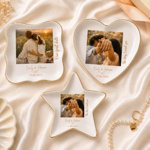 Peut inclure: Trois coupelles à bijoux en céramique blanche avec des bords dorés, en forme de carré, de cœur et d'étoile. Chaque coupelle présente une photo personnalisée, les noms Emily & Johnson, une date et le texte Our first date ou The day I said yes.