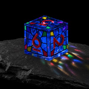 May include: A translucent blue cube-shaped die featuring a stained-glass pattern with red, yellow, and green accents. The faces display large red numbers, including a six and a two, with light refracting through the material to create colorful patterns.