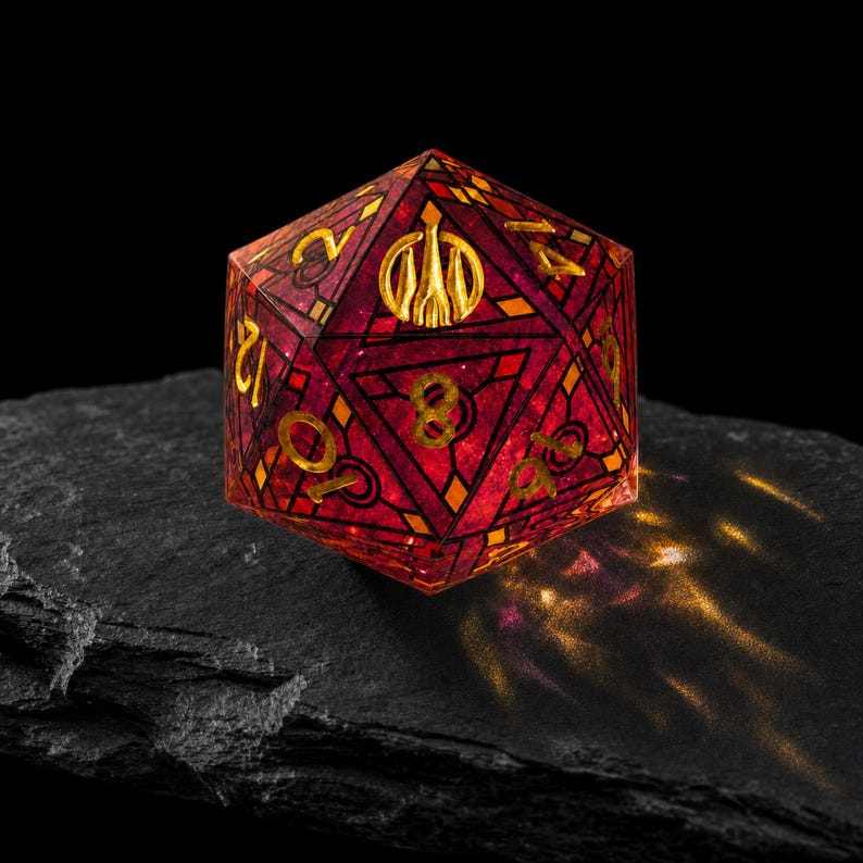 May include: A twenty-sided die featuring a translucent deep red resin body with intricate black geometric line patterns and gold-colored numbers. The top face displays a stylized gold emblem of a three-pronged crest instead of a number.